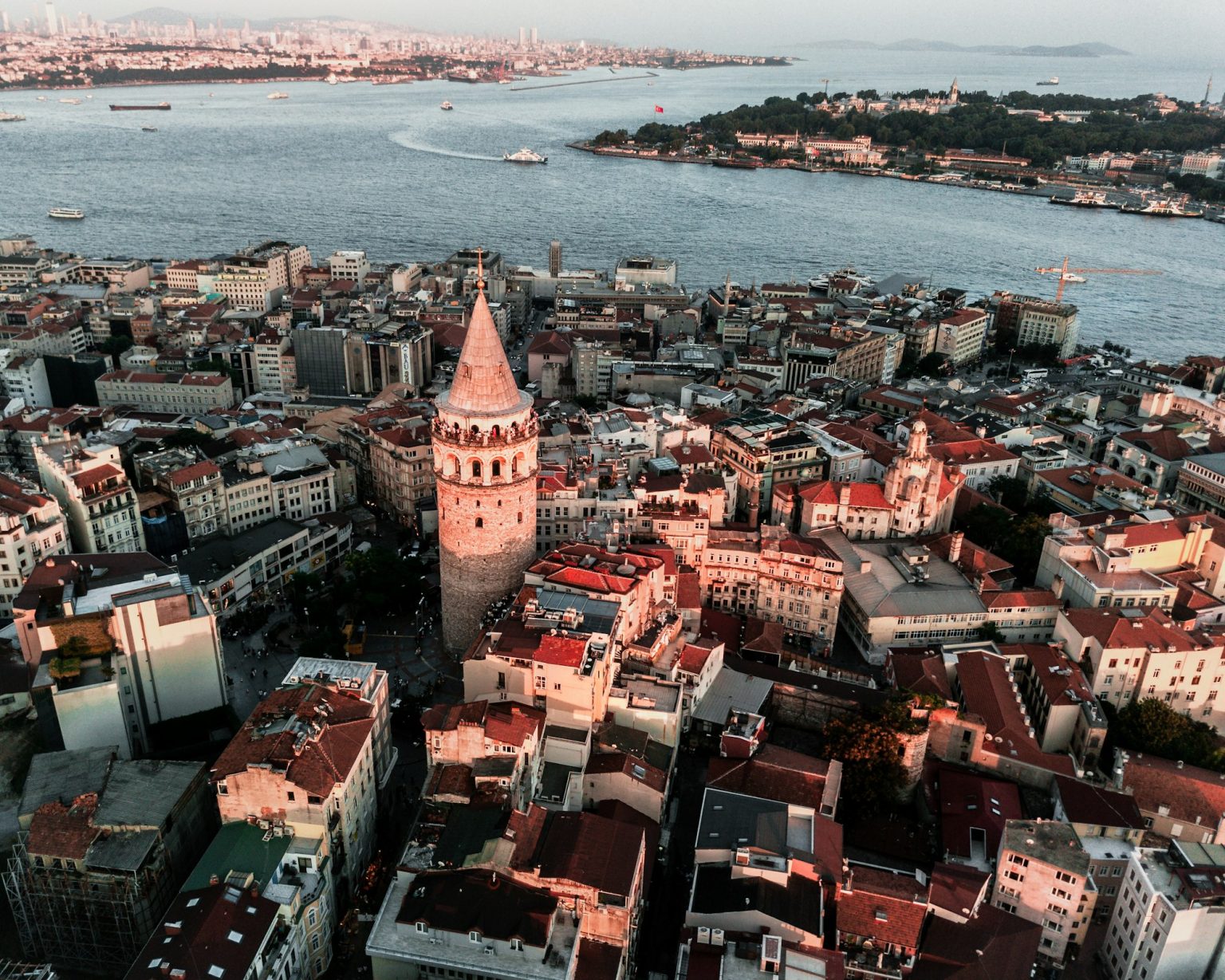 Drone view of the Galata Tower surrounded by buildings and the Bosphorus in Istanbul, Turkey